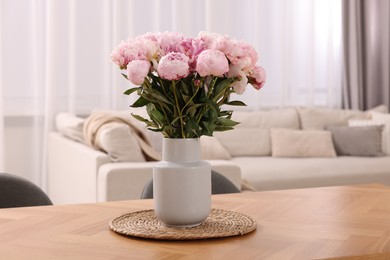 Vase with pink peonies on wooden table in dining room