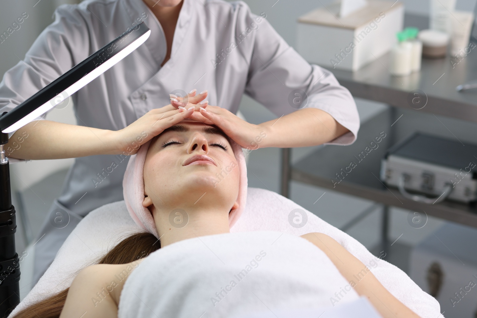 Photo of Cosmetologist making face massage to client in clinic, closeup