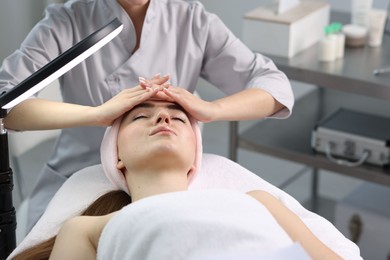 Photo of Cosmetologist making face massage to client in clinic, closeup