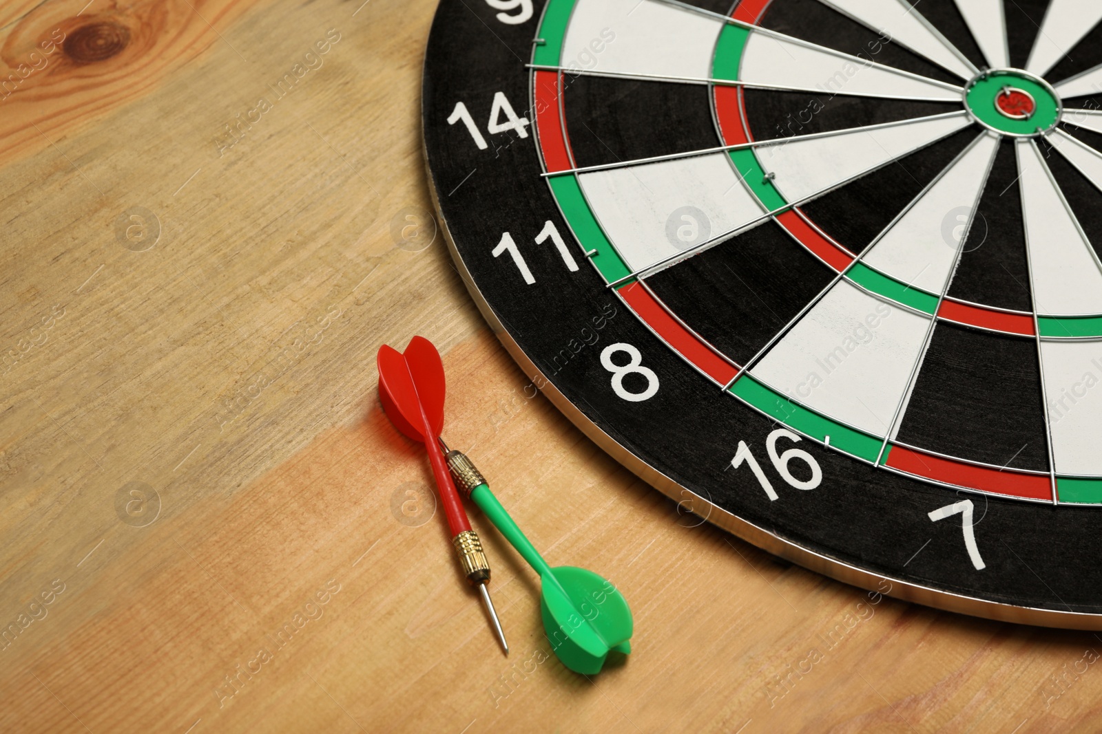 Photo of Dart board with color arrows on wooden background. Space for text