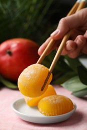 Photo of Woman eating delicious mochi with chopsticks at table, closeup. Traditional Japanese dessert