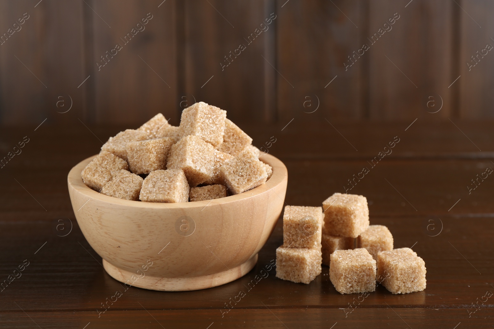 Photo of Many brown sugar cubes on wooden table