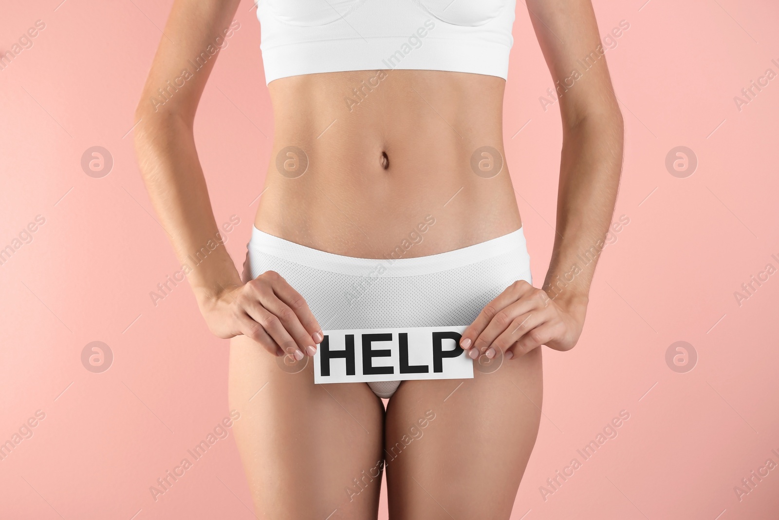 Photo of Young woman holding card with word HELP on color background. Gynecology concept