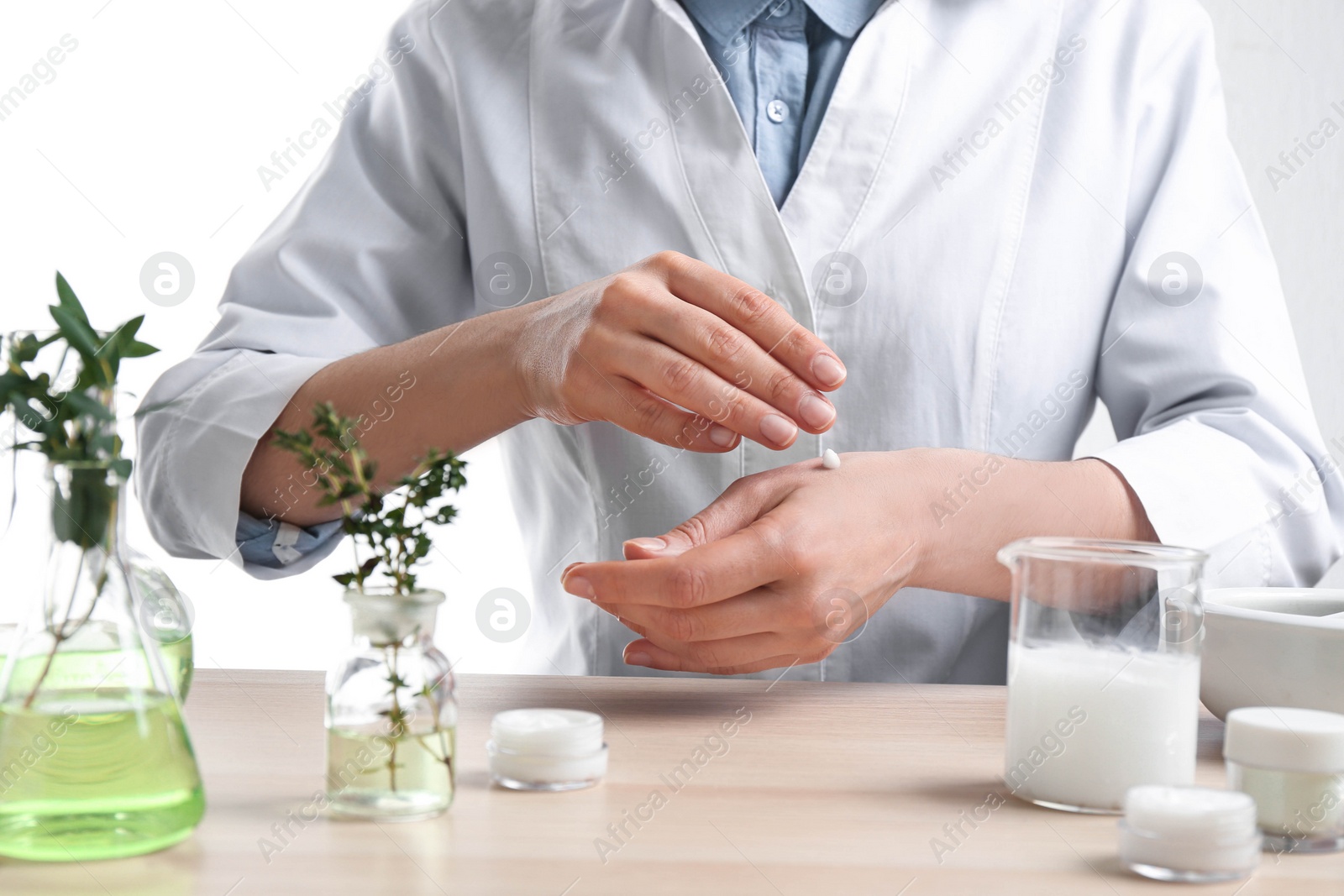 Photo of Woman applying natural cream onto hand in cosmetic laboratory, closeup