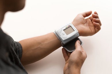 Man checking blood pressure with sphygmomanometer at table, closeup. Cardiology concept