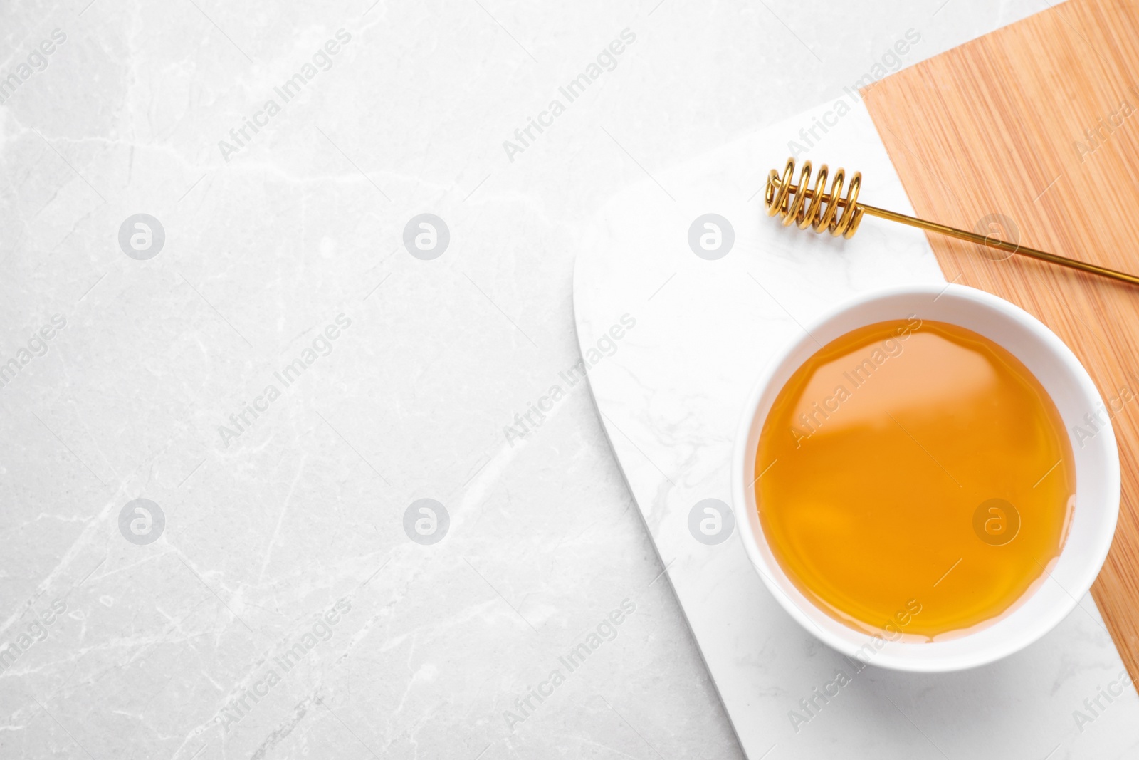 Photo of Tasty honey on light grey marble table, top view. Space for text