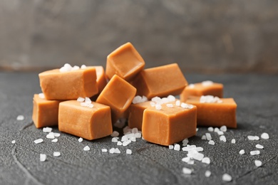 Delicious caramel candies with salt on dark background