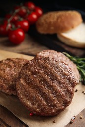 Photo of Tasty grilled hamburger patties with seasonings on wooden table, closeup