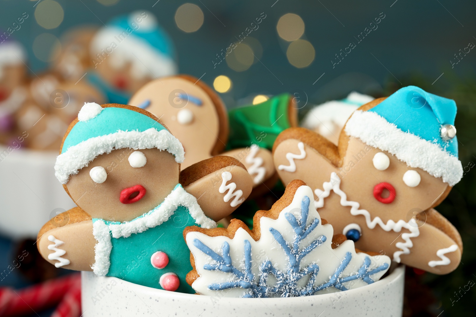 Photo of Delicious homemade Christmas cookies in bowl against blurred festive lights, closeup