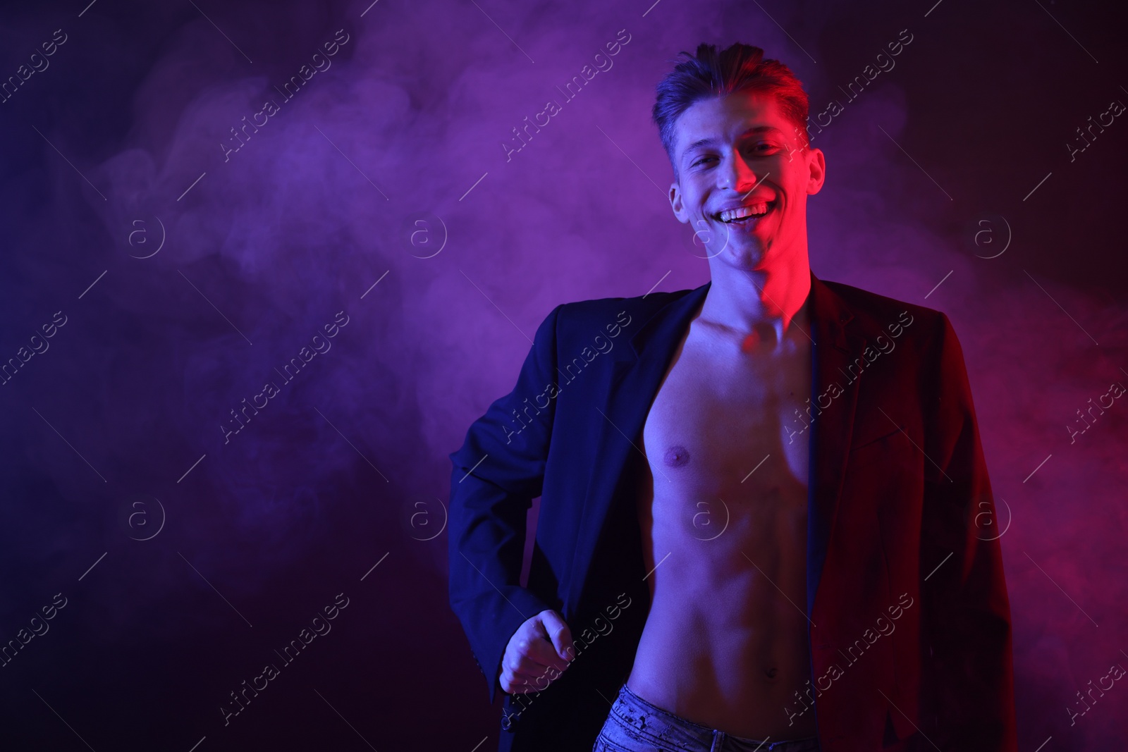 Photo of Sexy young man in neon lights with smoke effect. Space for text