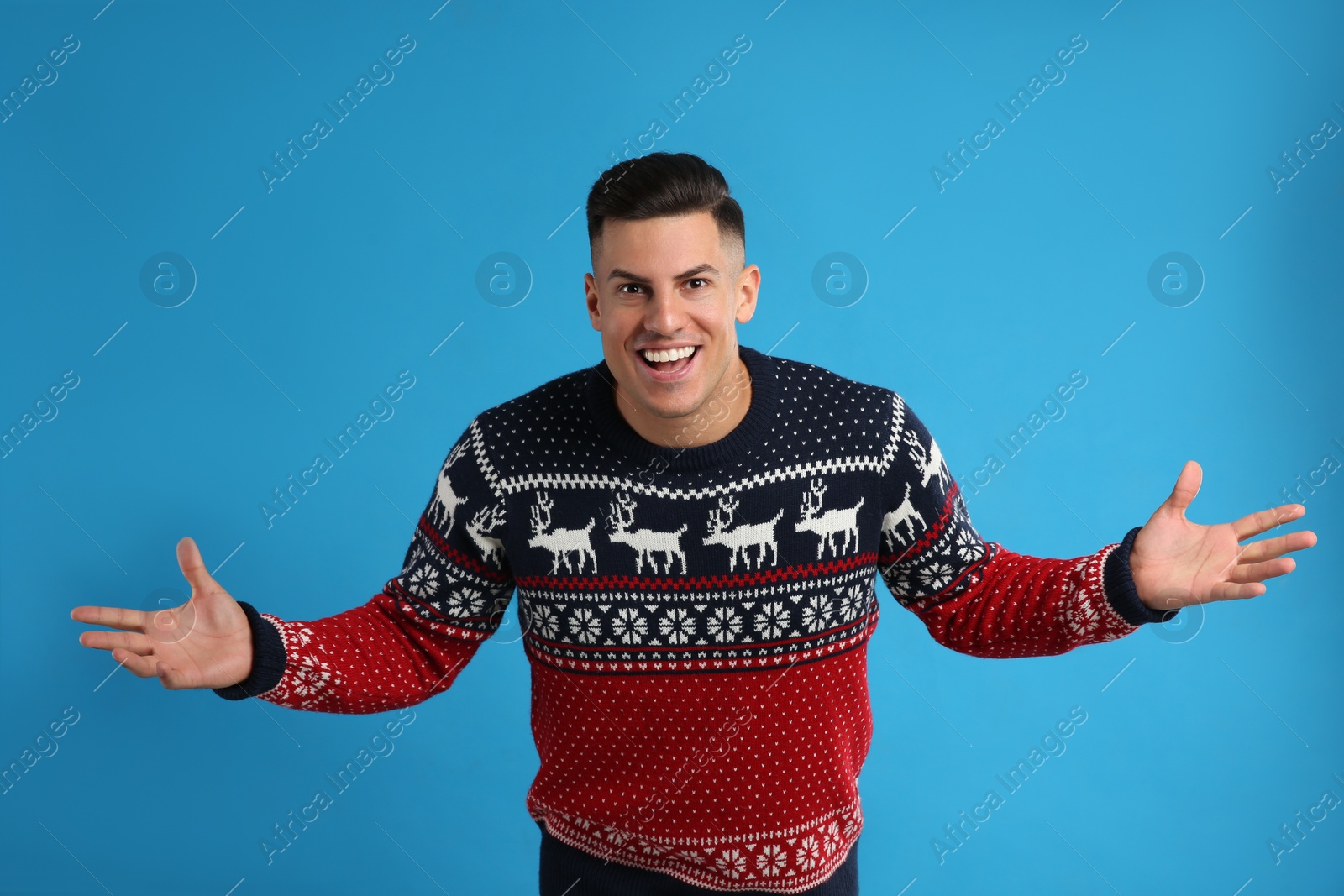 Photo of Excited man in Christmas sweater on blue background
