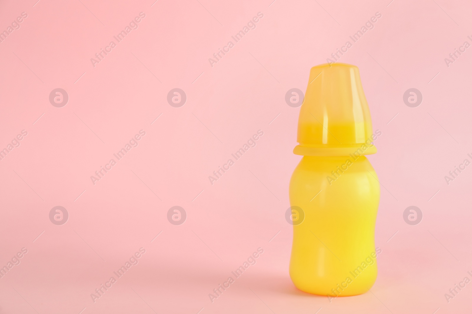 Photo of Feeding bottle with infant formula on pink background, space for text. Baby milk