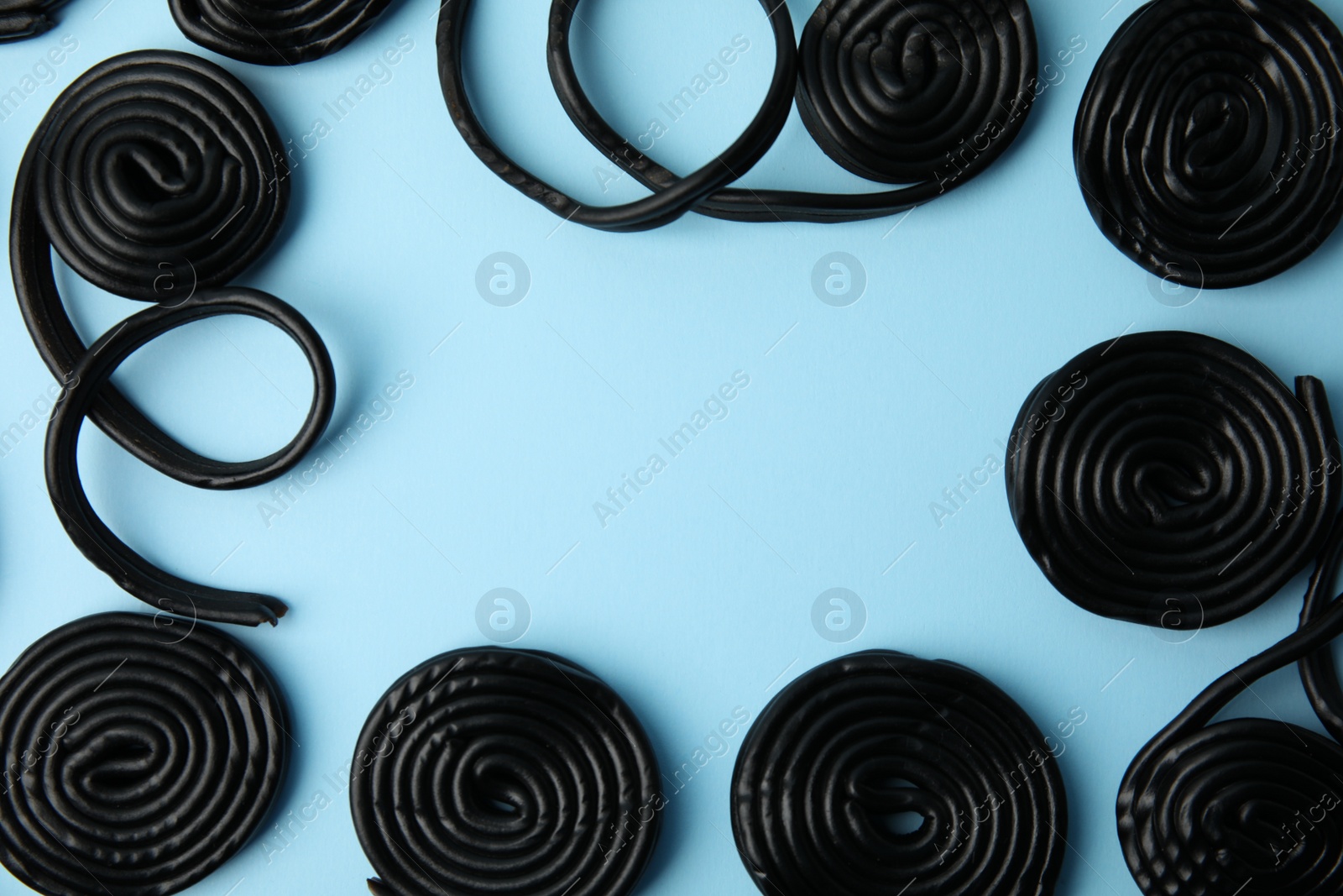 Photo of Tasty liquorice candies on light blue background, flat lay. Space for text