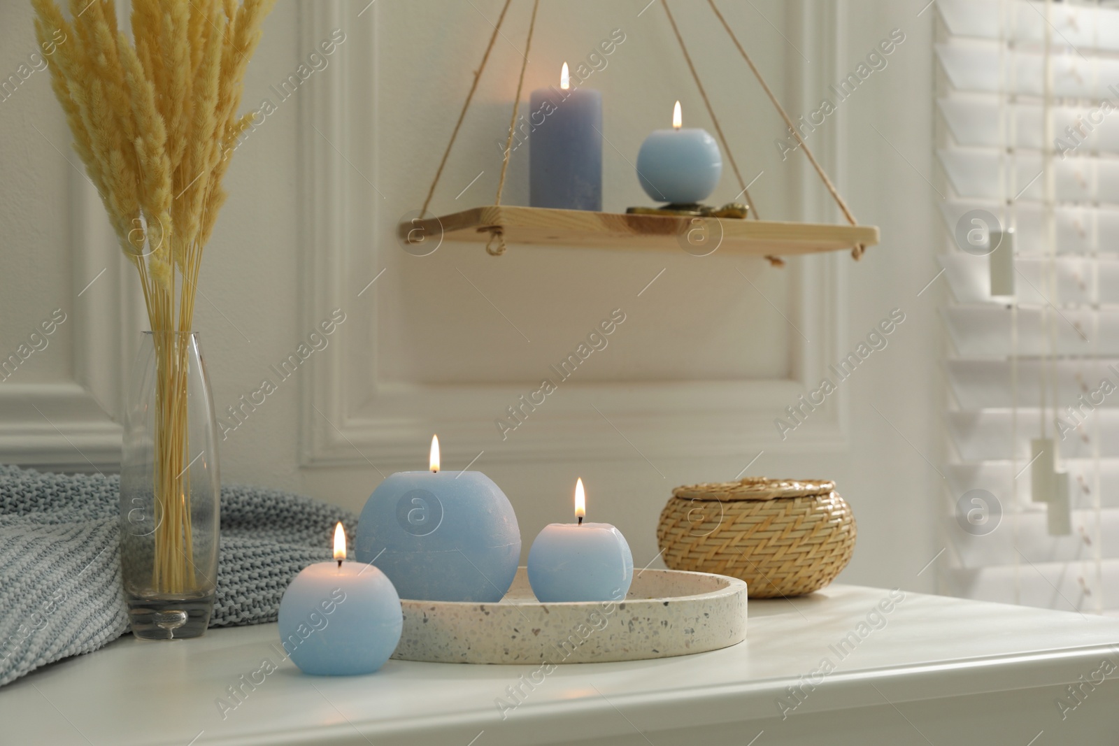 Photo of Burning candles on white countertop in room