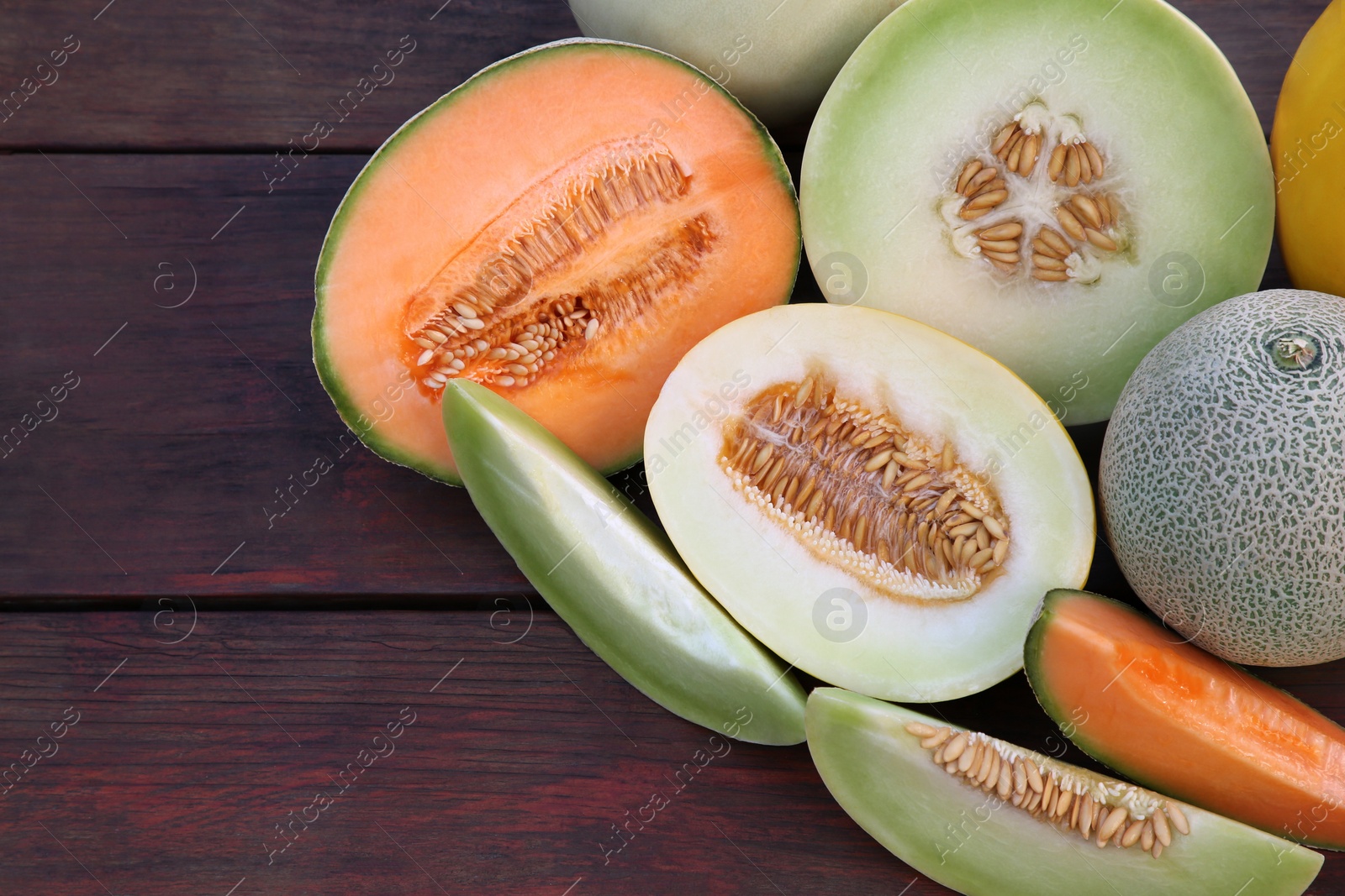 Photo of Different types of tasty ripe melons on wooden table, flat lay. Space for text