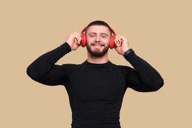 Photo of Handsome sportsman with headphones on brown background