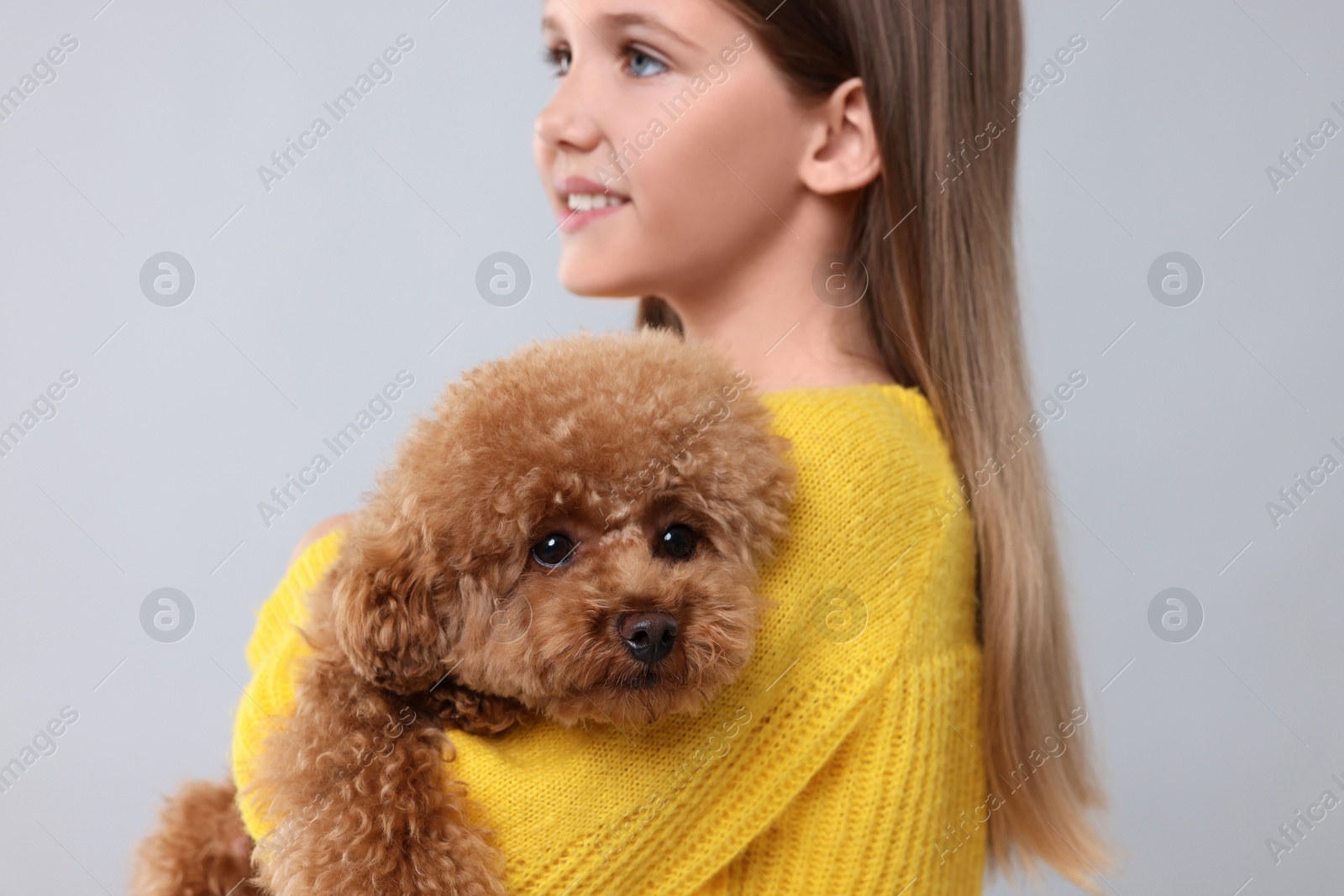 Photo of Little child with cute puppy on light grey background. Lovely pet