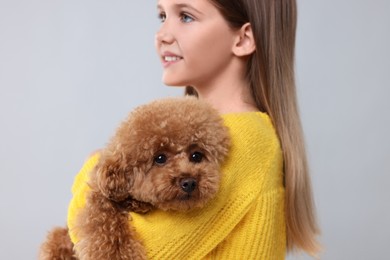 Little child with cute puppy on light grey background. Lovely pet