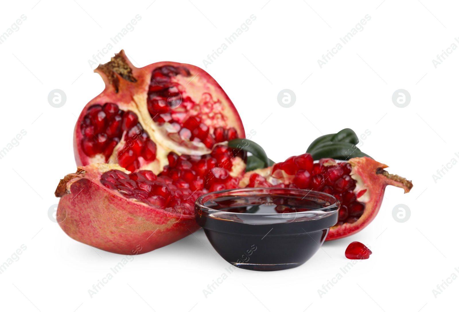 Photo of Tasty pomegranate sauce in bowl, leaves and fruits isolated on white