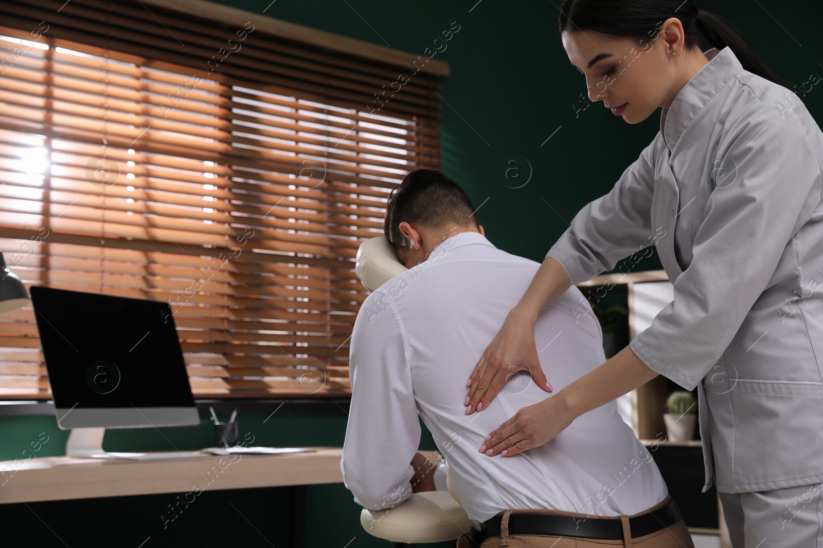 Photo of Man receiving massage in modern chair indoors