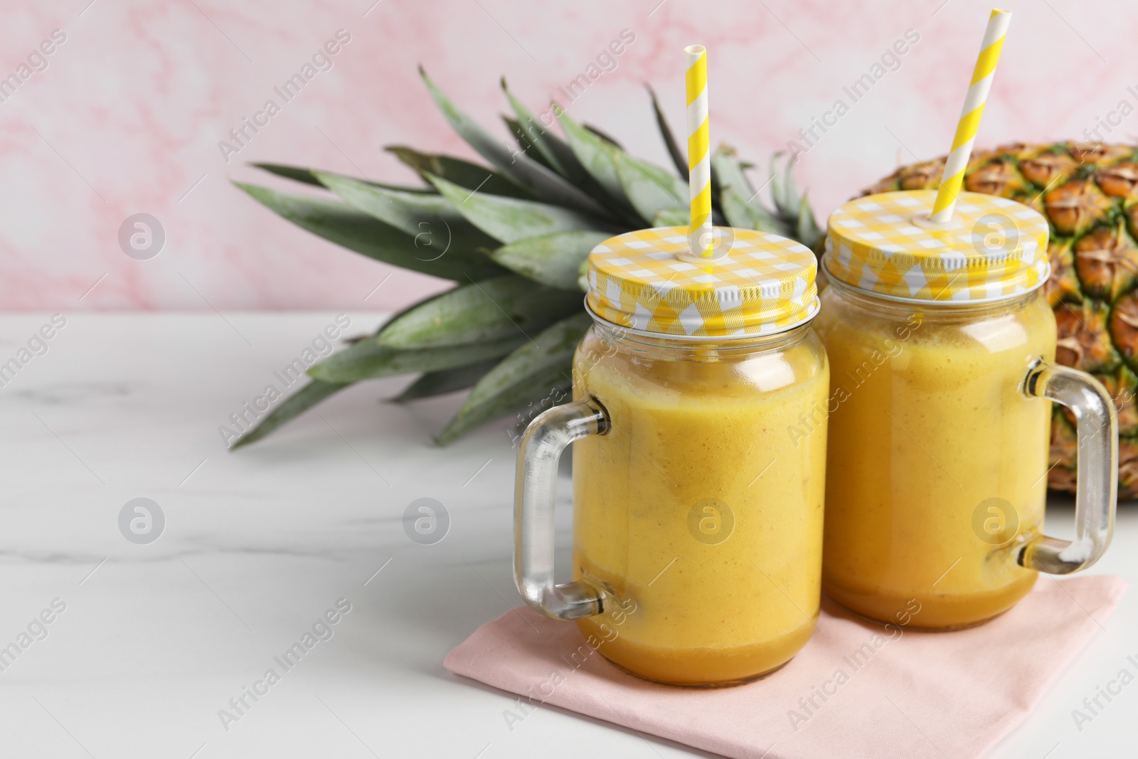 Photo of Tasty pineapple smoothie and fruit on white marble table, closeup. Space for text