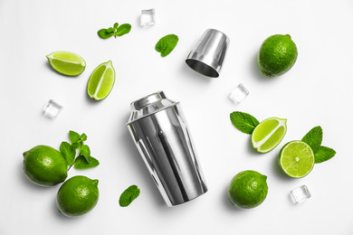 Photo of Flat lay composition with fresh juicy limes, mint, ice cubes and cocktail shaker on white background