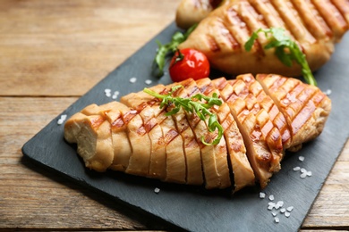 Photo of Tasty cut grilled chicken fillet with arugula on wooden table, closeup