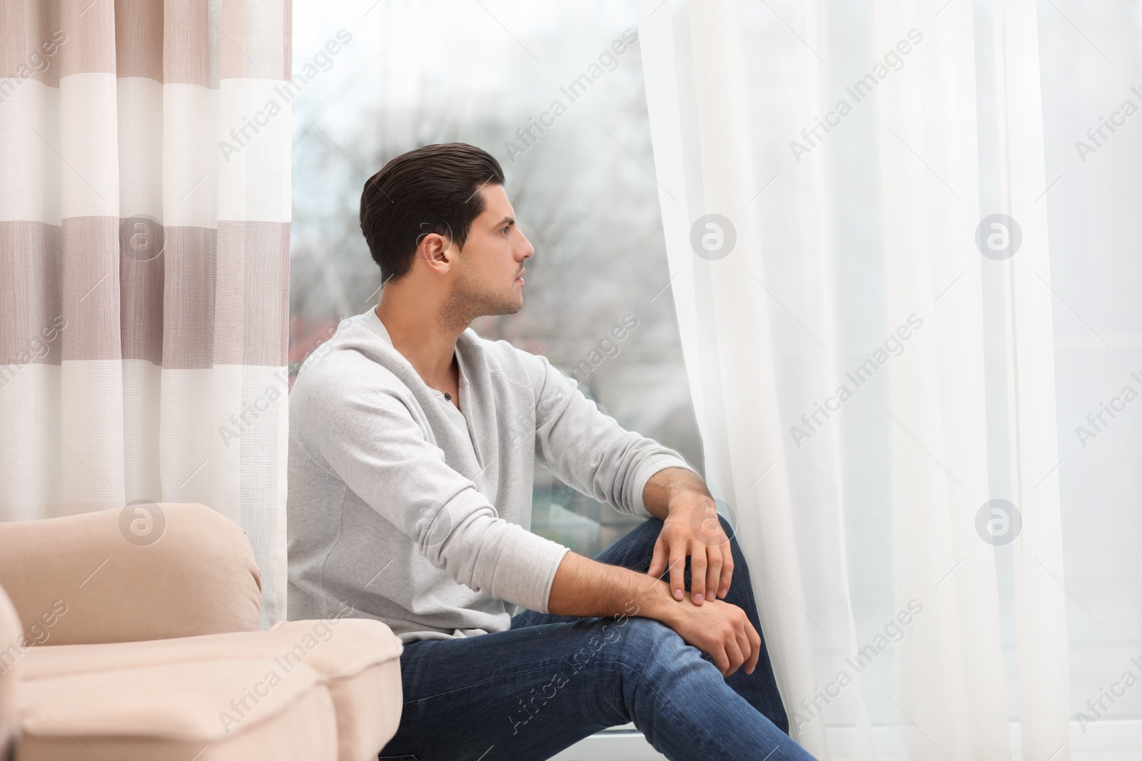 Photo of Handsome man resting near window at home