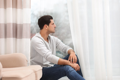 Photo of Handsome man resting near window at home