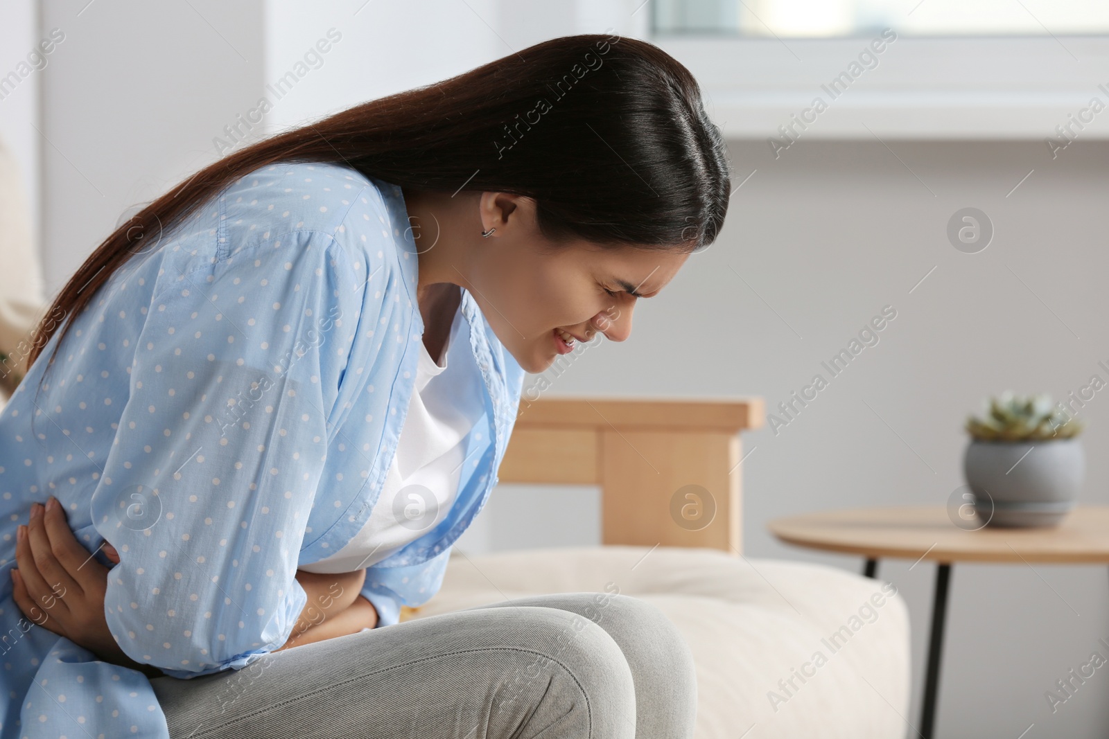 Photo of Young woman suffering from menstrual pain at home