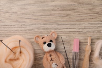 Photo of Felted bear, wool and tools on wooden table, flat lay. Space for text