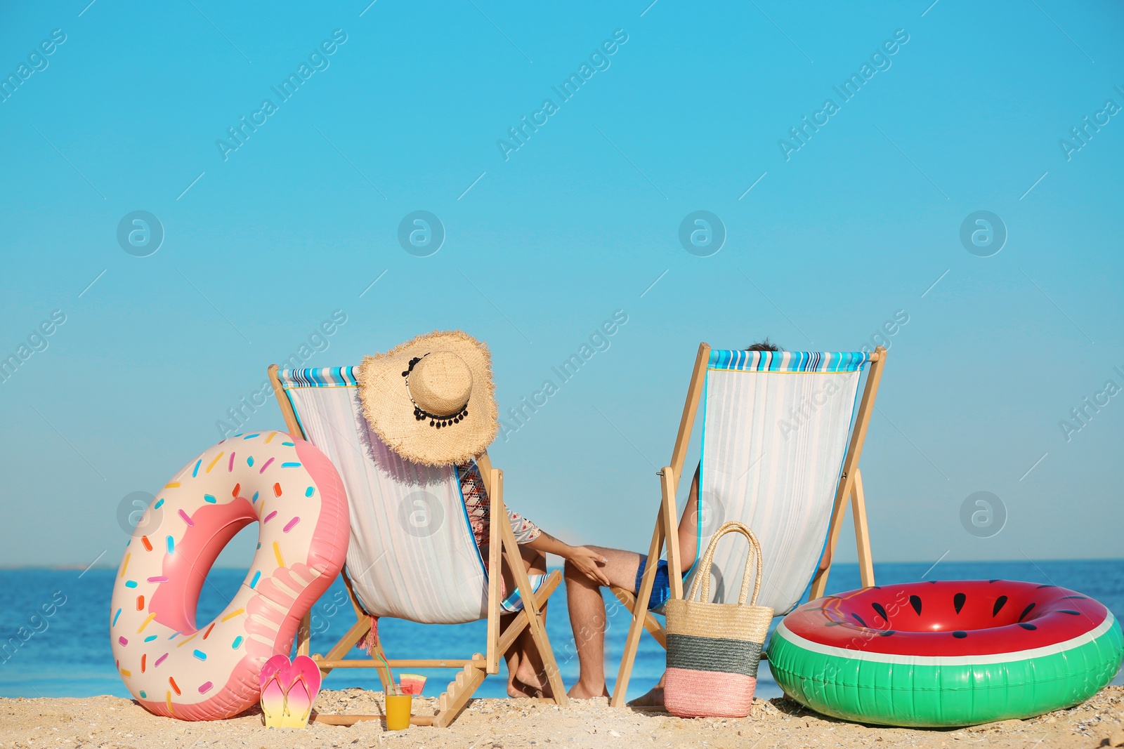 Photo of Young couple in beach chairs at seacoast
