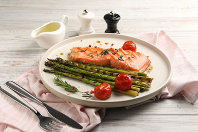 Photo of Tasty grilled salmon with tomatoes, asparagus and spices served on table