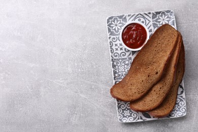 Photo of Plate with crispy rusks and dip sauce on light table, top view. Space for text