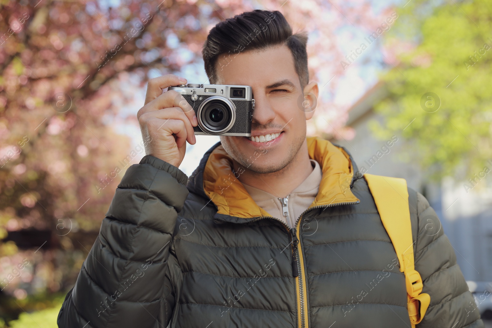 Photo of Happy male tourist with camera outdoors on spring day