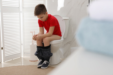 Boy suffering from hemorrhoid on toilet bowl in rest room