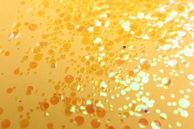 Photo of Shiny bright golden glitter on yellow background
