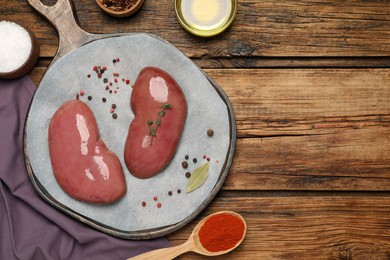 Photo of Fresh raw pork kidneys and ingredients on wooden table, flat lay. Space for text