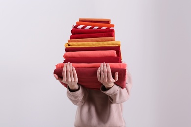 Photo of Woman holding stack of clean bed linens on light background