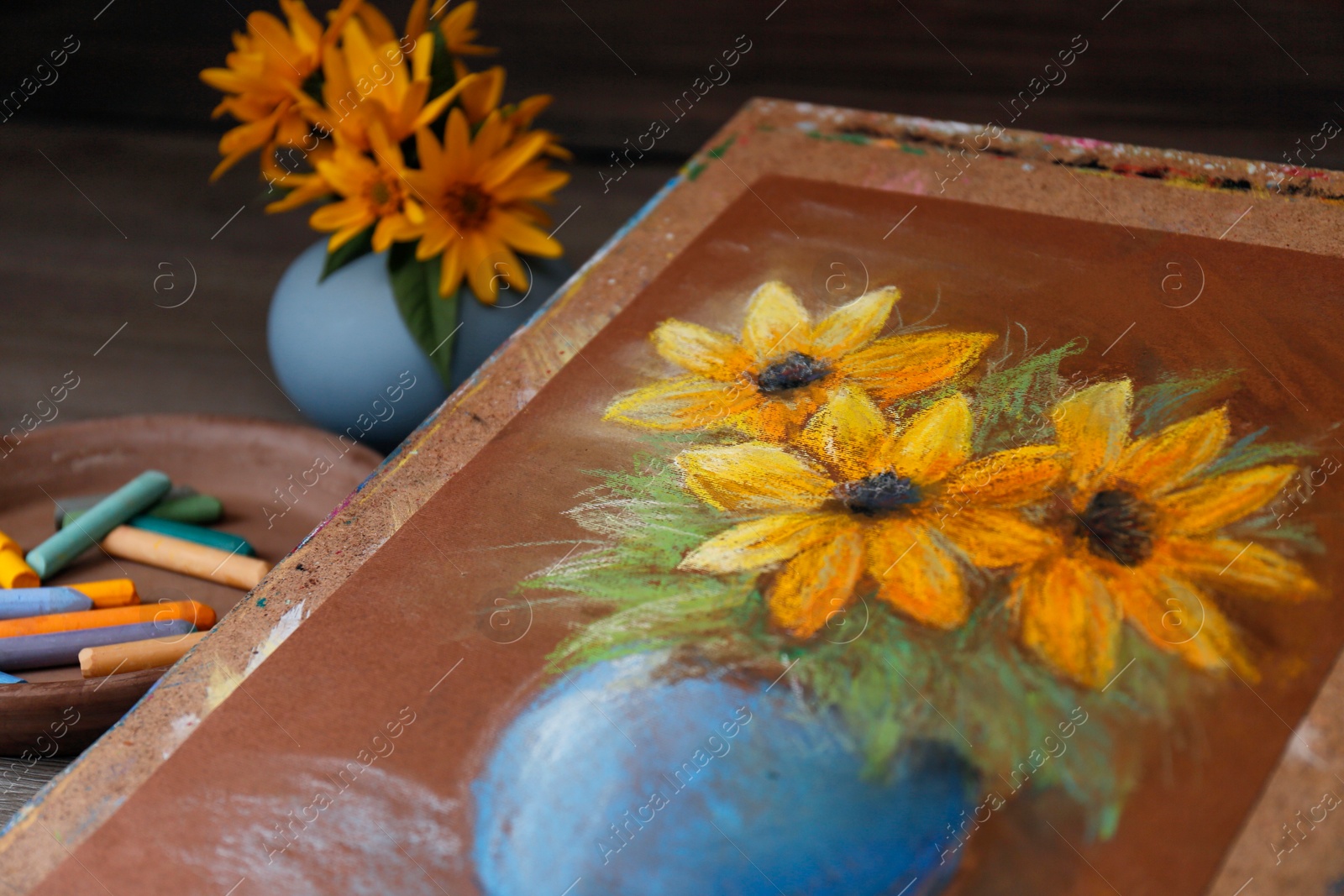 Photo of Pastel drawing of beautiful yellow flowers in vase on table, closeup