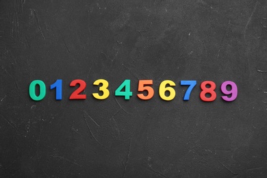 Photo of Colorful magnetic numbers on black stone background, flat lay