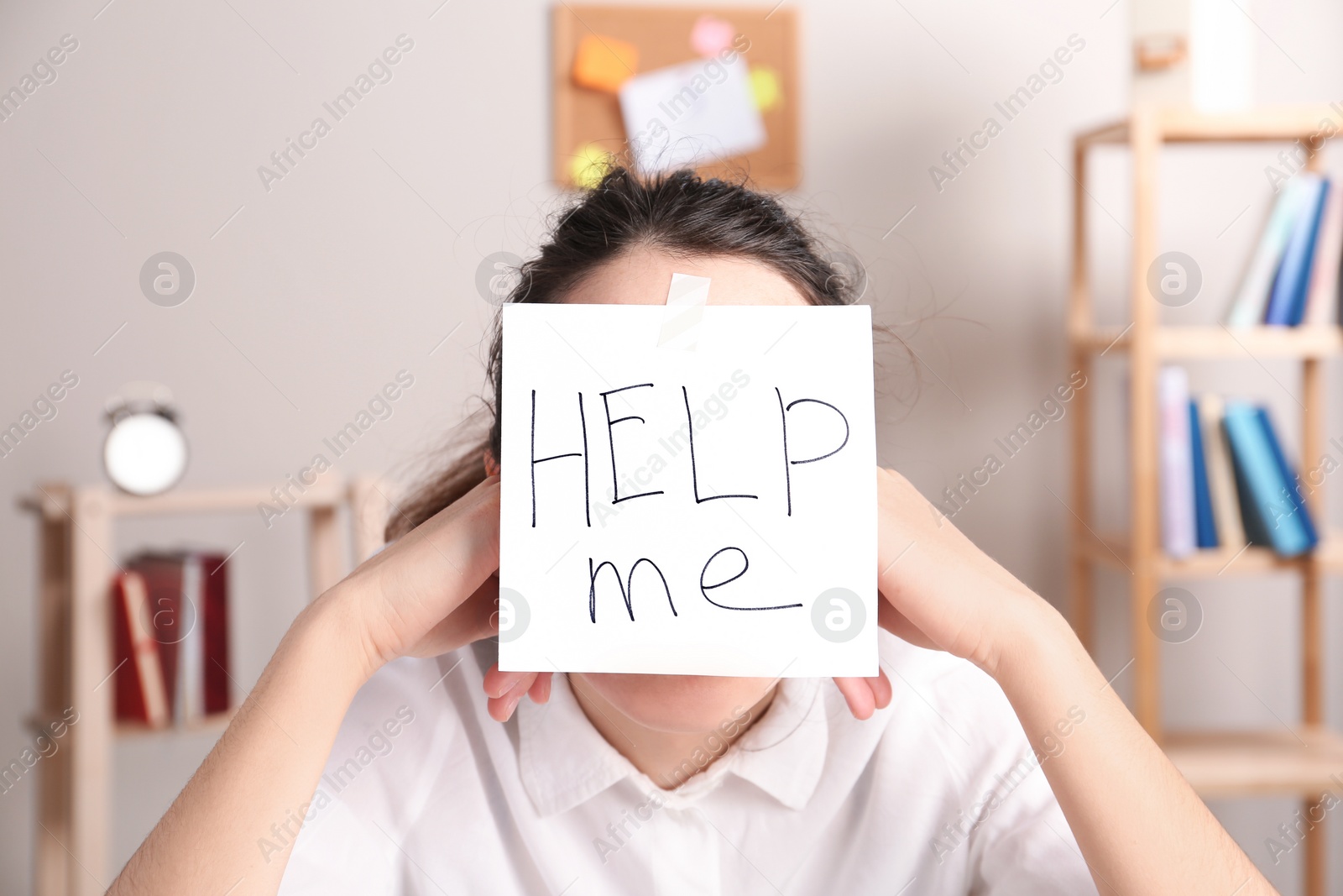 Photo of Young woman with note HELP ME on forehead indoors