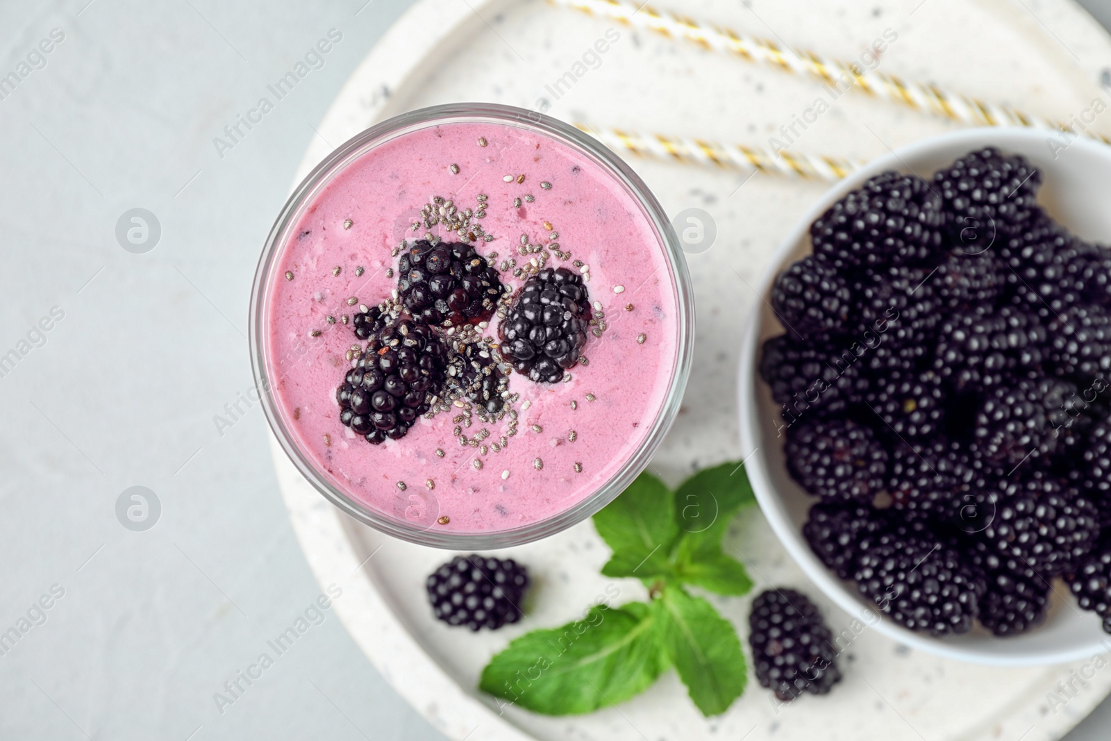 Photo of Delicious blackberry smoothie in glass served on light table, top view