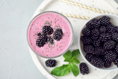 Delicious blackberry smoothie in glass served on light table, top view