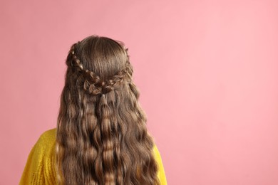 Little girl with braided hair on pink background, back view. Space for text