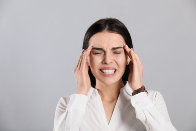 Photo of Woman suffering from migraine on grey background