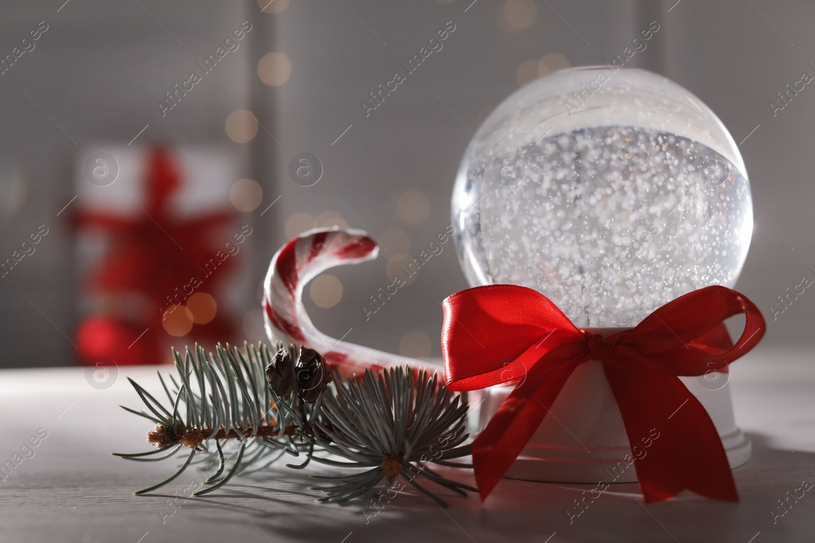 Photo of Christmas snow globe with red bow on table. Space for text