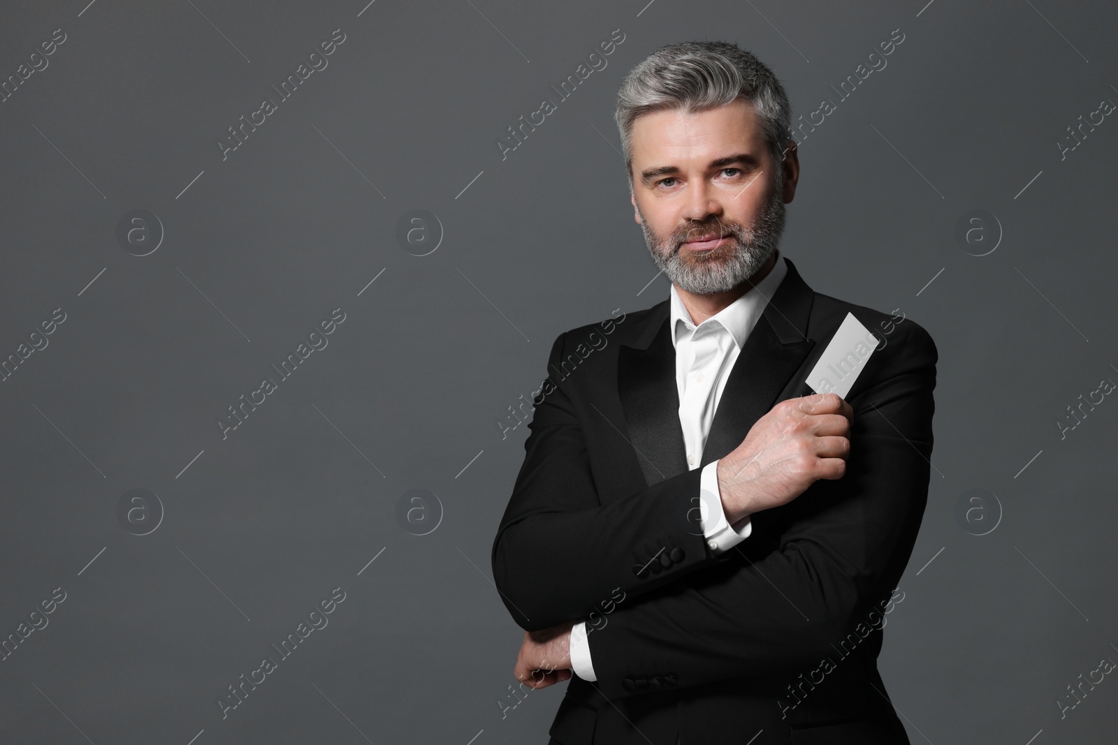 Photo of Handsome businessman holding blank business card on grey background. Space for text