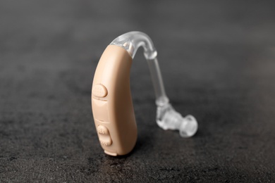Photo of Hearing aid on grey table, closeup. Medical device