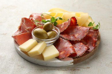 Photo of Serving board with delicious cured ham, cheese, sausage and olives on light table